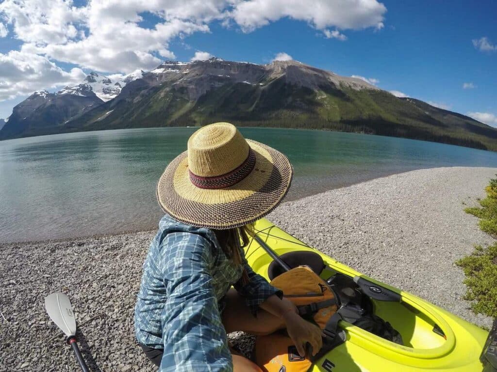 Woman kneeling by kayak on edge of lake