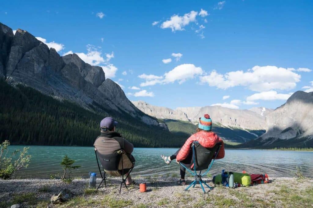 Two campers sitting in chairs at edge of Lake Maligne in Jasper National Park in Alberta