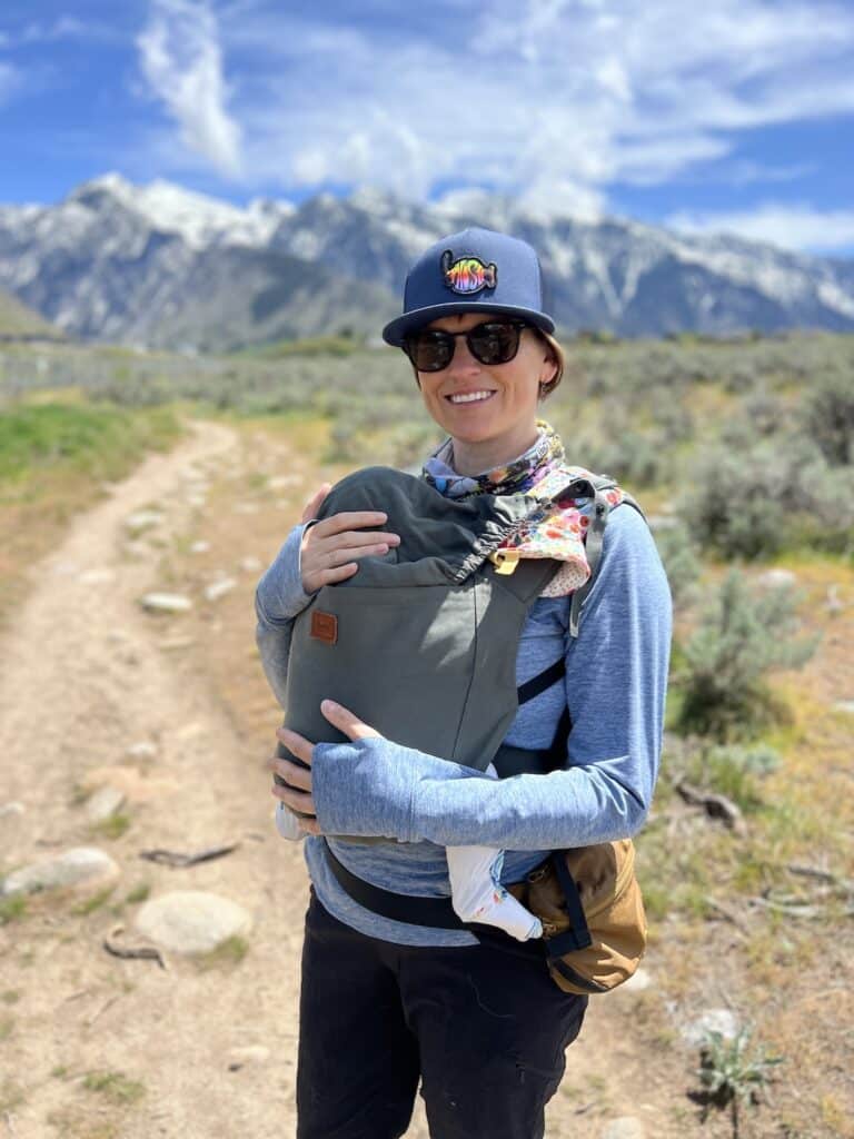 Kristen Bor wearing her baby in front of Salt Lake City's Wasatch Mountains