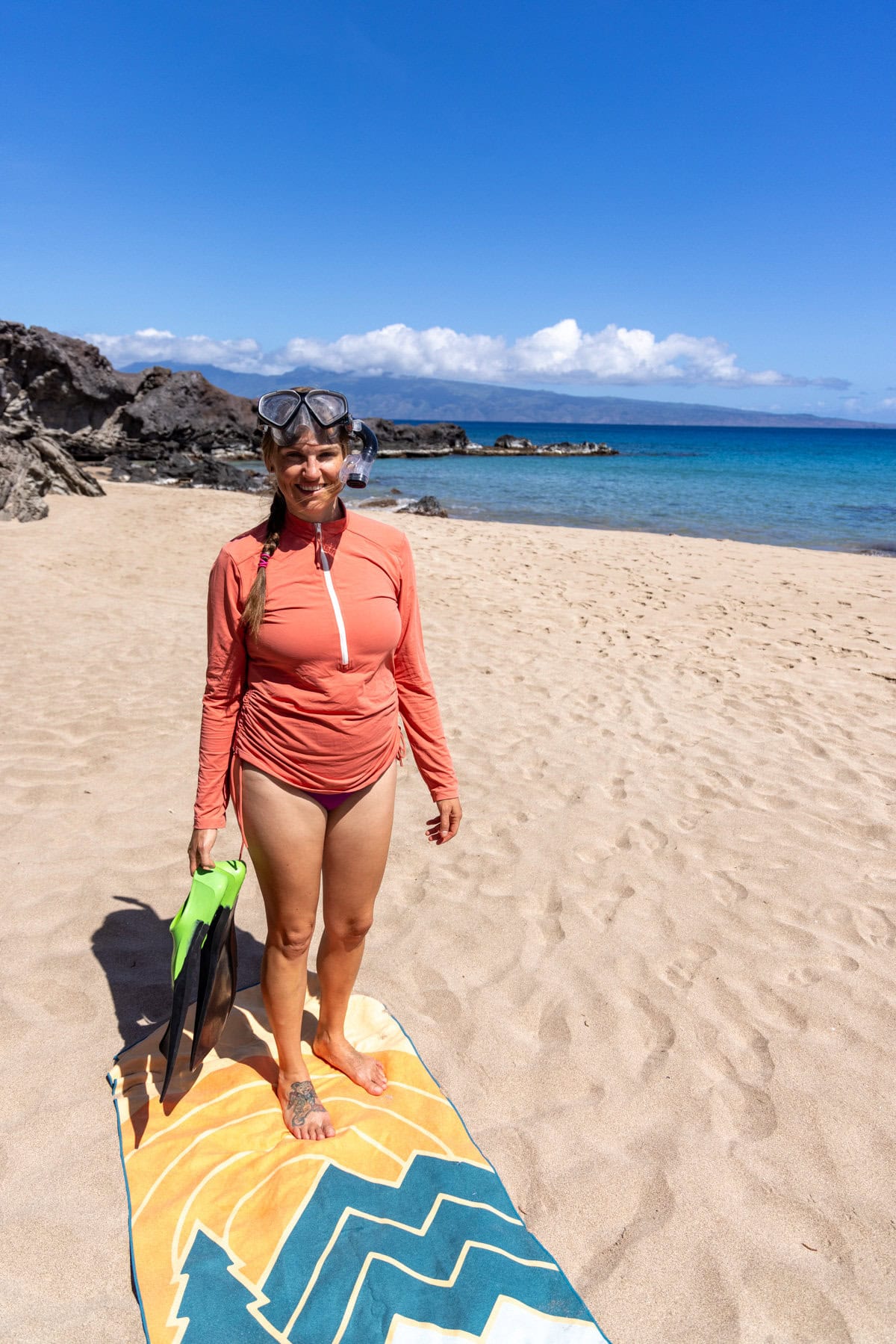 Kristen Bor standing on a towel on the beach in Maui with a snorkel on her head