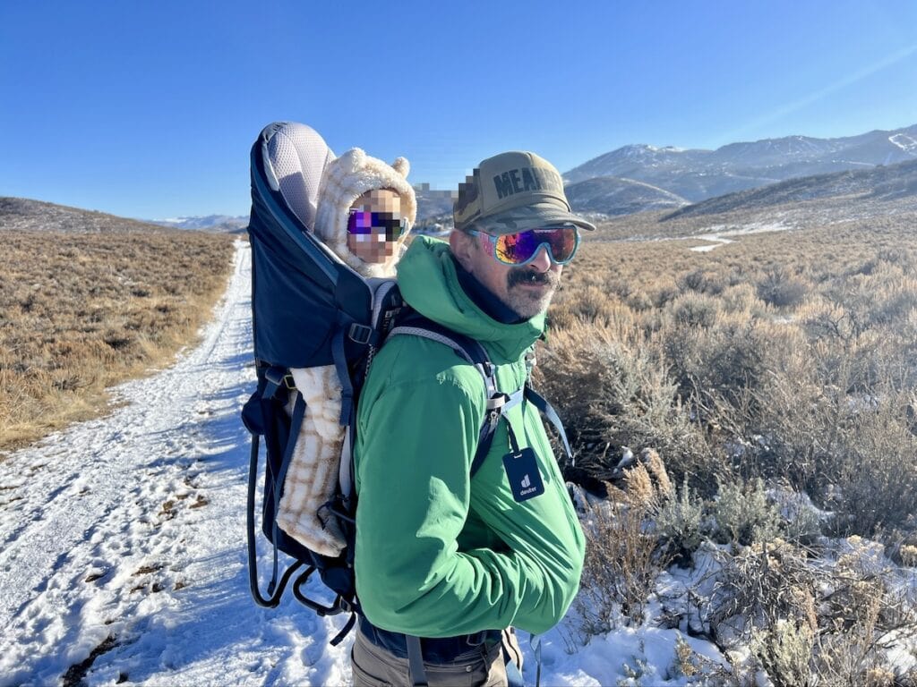 Man hiking in winter with a baby in backpack