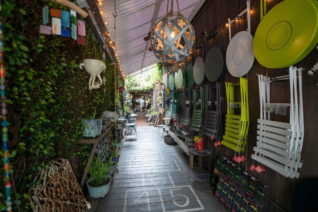 Narrow walkway lined with a wall of ivy and shop souvenirs in Ojai, California