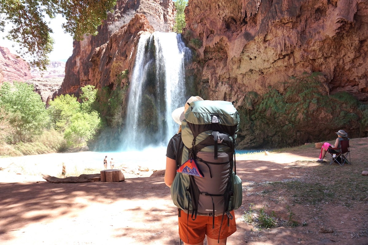 Woman with backpacking pack on at the base of Havasu Falls