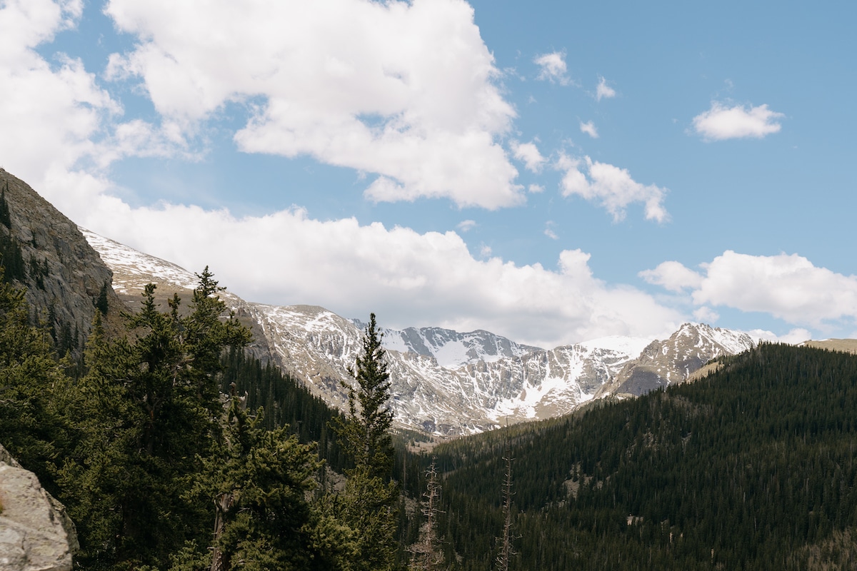 View of mountains with trees and a blue sky with puffy clouds in Colorado