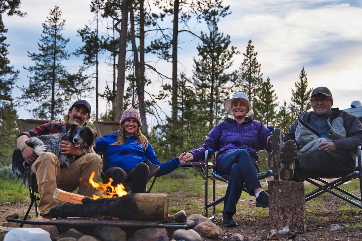 A campfire scene with four people sitting in chairs around a fire