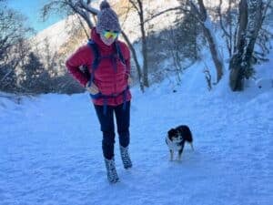 Bearfoot Theory founder Kristen Bor winter hiking with her mini aussie dog on a snowy trail in Utah