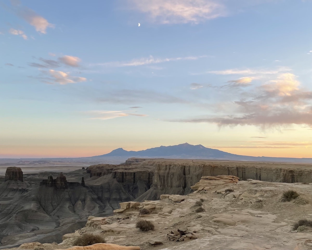 A crescent moon in a blue sky with pink and orange clouds during sunset at Moonscape Overlook