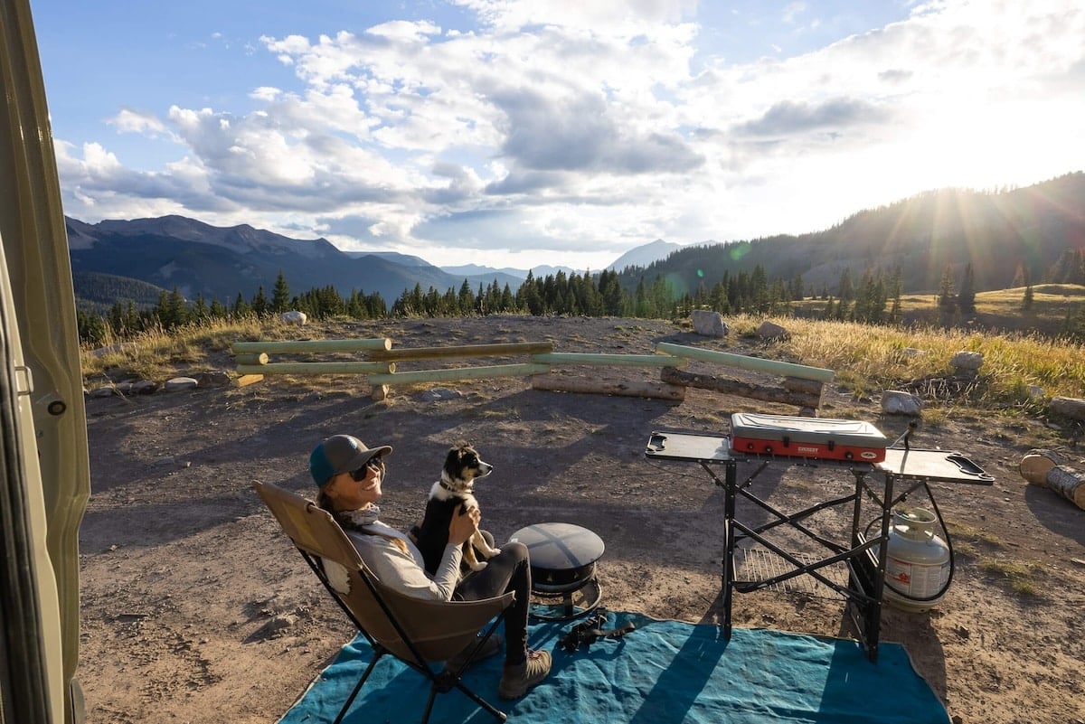 Kristen Bor sitting in camp chair next to camp table at a campsite in Colorado