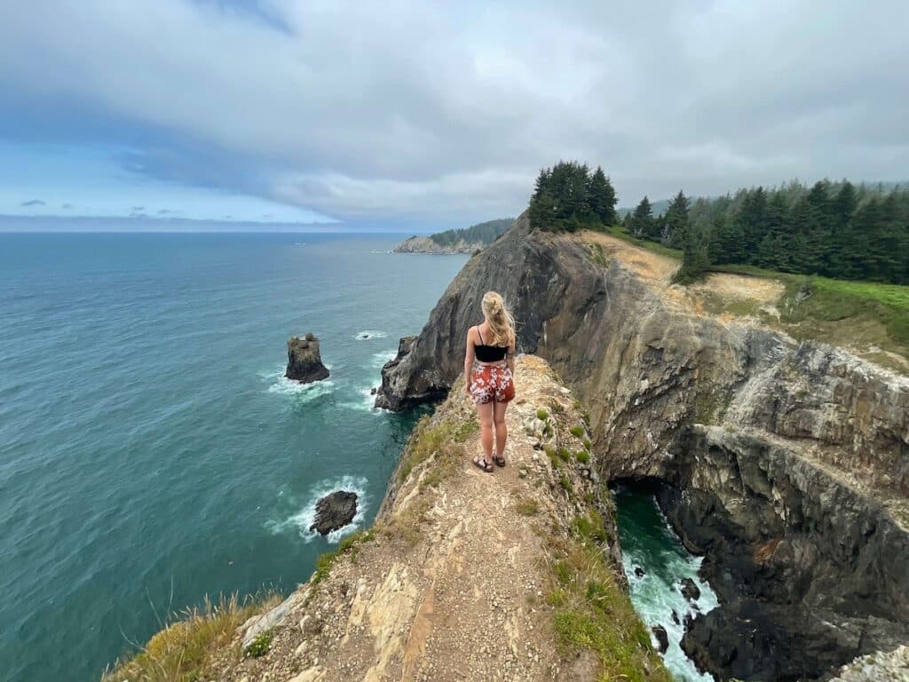 Woman standing at scenic lookout on to the Pacific Ocean at Oswald West State Park in Oregon