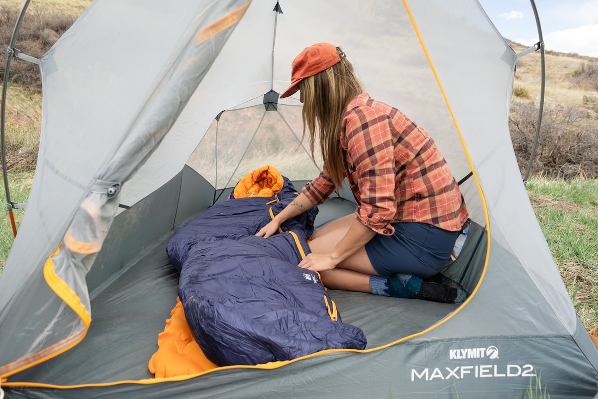 Woman setting up the REI Magma sleeping bag inside of a tent