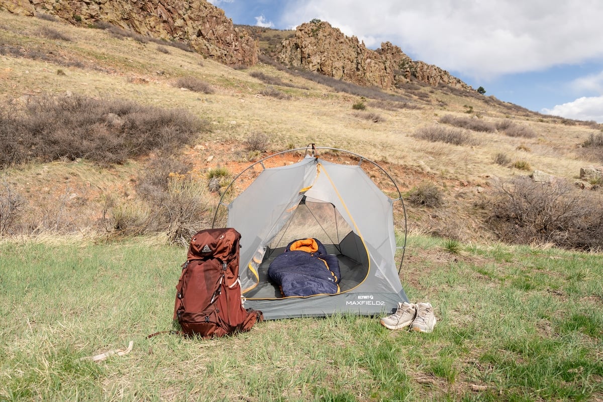 The REI Magma sleeping bag inside of a tent with green grass and rocks behind it