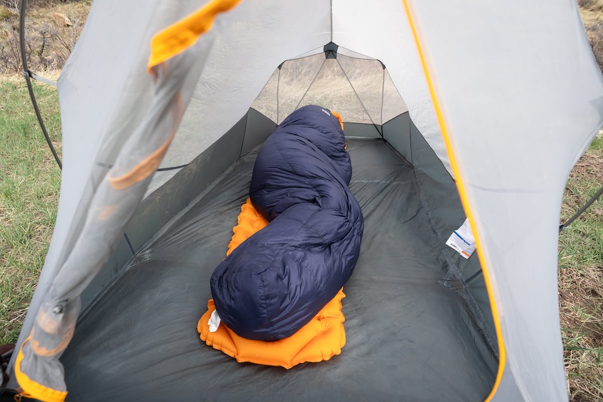 Woman sleeping on her side on a sleeping pad in the REI Magma sleeping bag