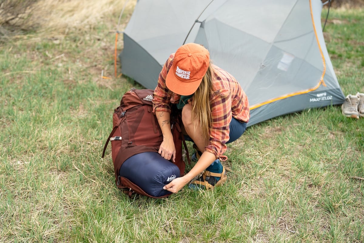 A woman pulling the REI Magma sleeping bag out of a backpack