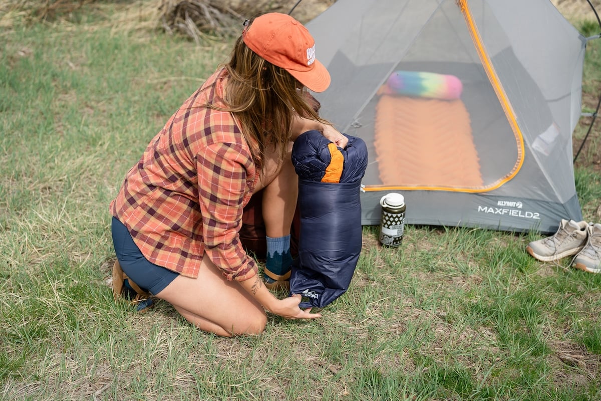 Woman pulling the REI Magma sleeping bag out of its stuff sack