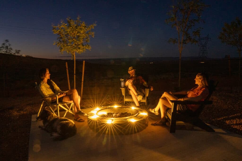 Three people sitting around a firepit at a campsite at Roam Horseshoe Bend RV Resort