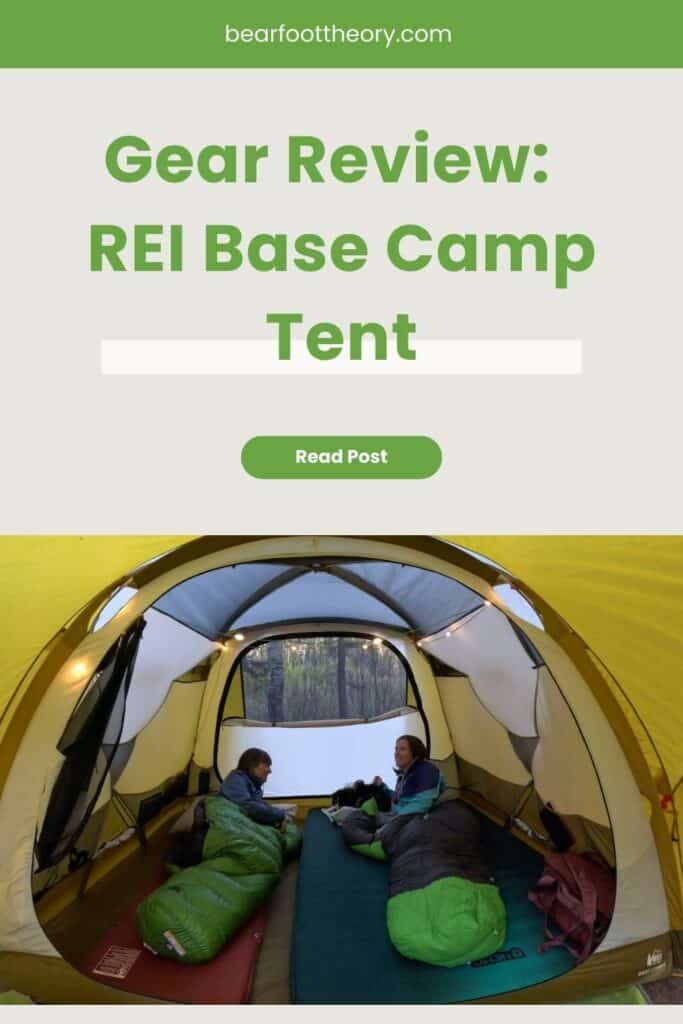 Two women laying in sleeping bags inside tent. Text reads Gear Review: REI Base Camp Tent