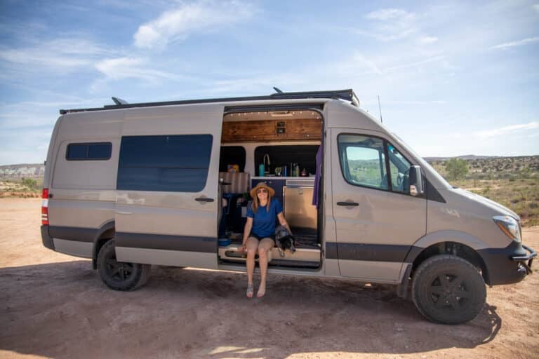 Kristen Bor sitting on edge of Sprinter Van in Moab on a hot summer day