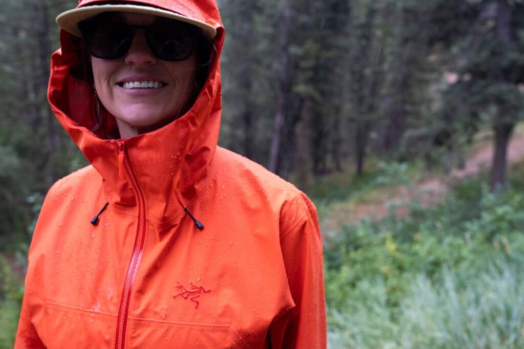 Kristen Bor wearing a red Arc'teryx Beta SL Rain Jacket with the hood on during a rainy hike