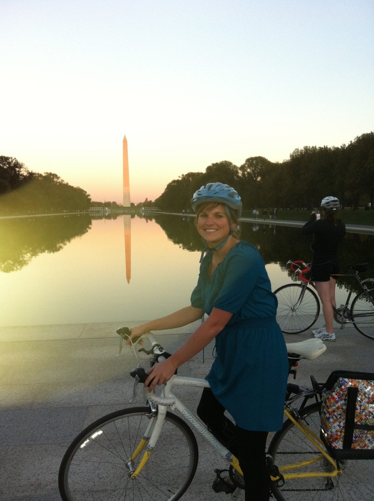 Kristen Bor on a bike in Washington DC in front of the Washington Monument at sunset