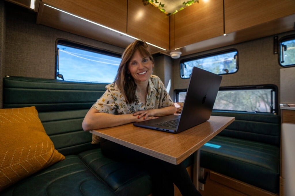 Kristen Bor working at the dinette inside the Rossmonster Baja Trail LX truck camper in the snow