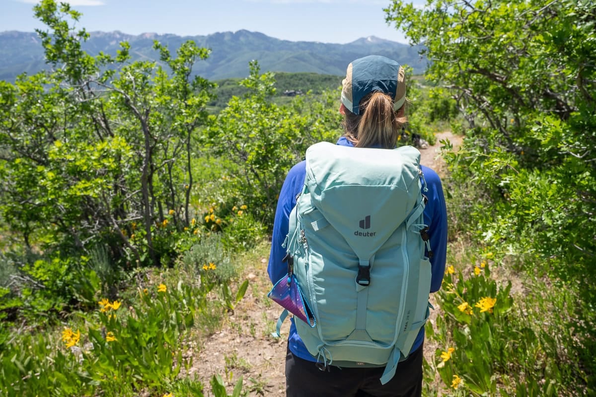Kristen Bor wearing the Deuter Trail 28 SL backpack on a trail in Park City with green foliage