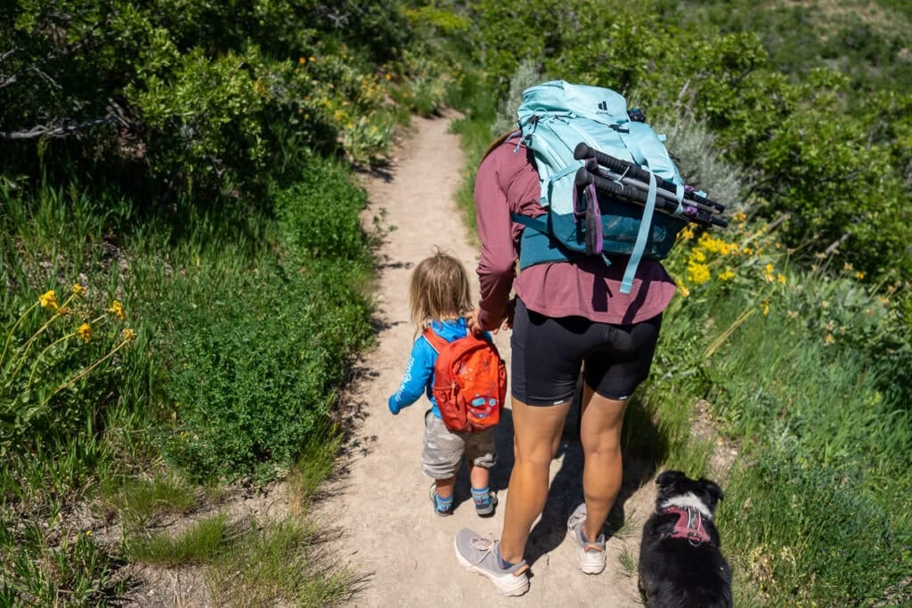 Kristen Bor and her toddler on a hiking trail. She is bending over to get something out of his backpack