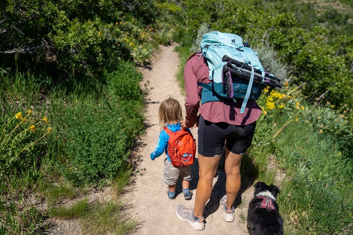 Kristen Bor and her toddler on a hiking trail. She is bending over to get something out of his backpack