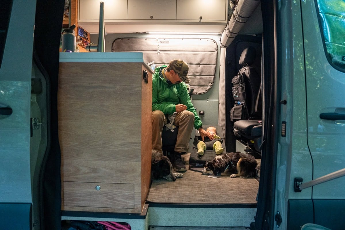 Dad and a baby sitting in a Sprinter camper van